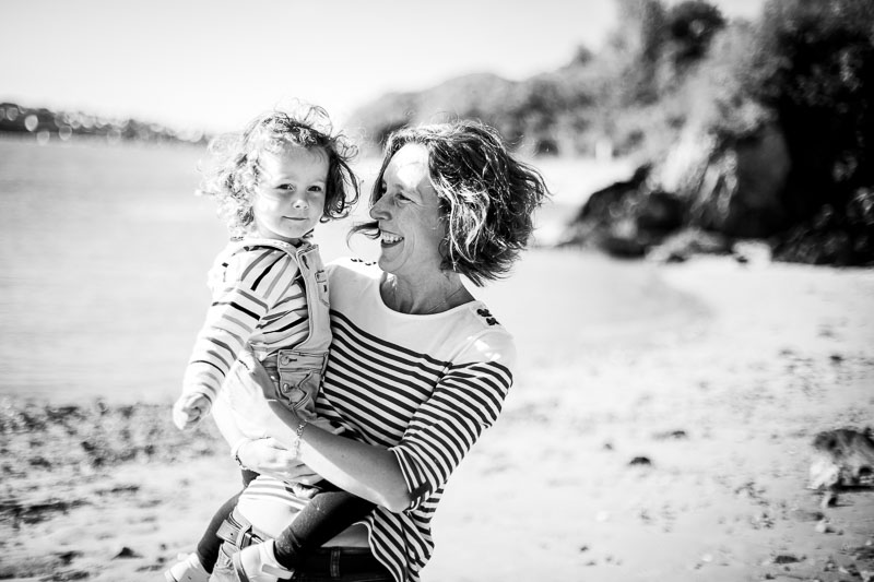 petite fille dans les bras de sa maman à la plage