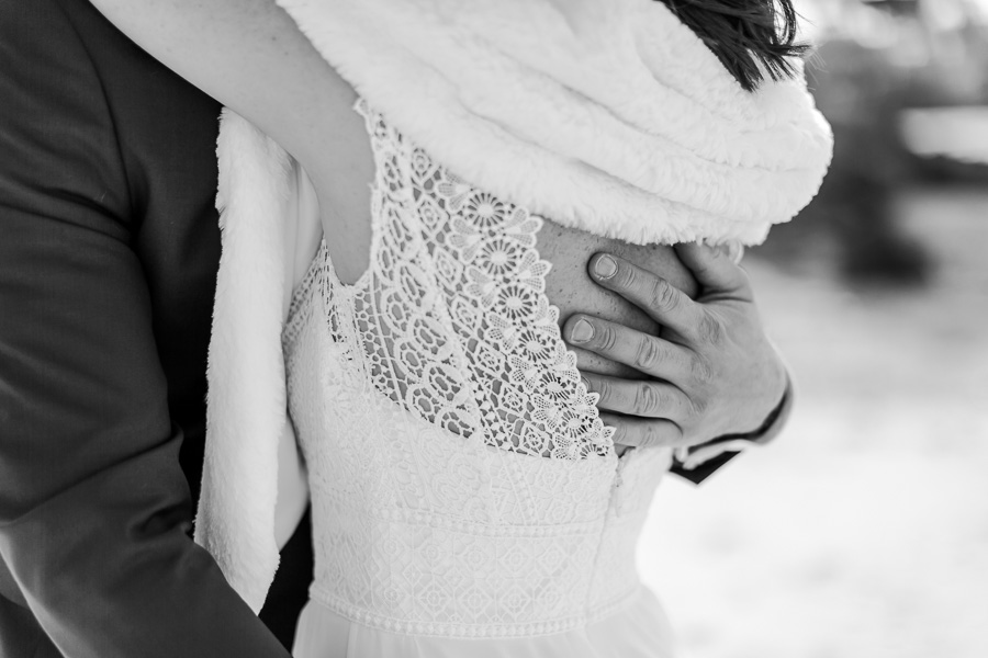 detail de la robe de la mariee enlacé par le marie