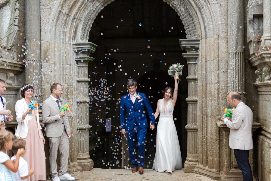 sortie de l'église des mariés heureux avec les bulles