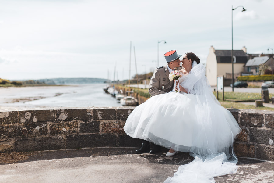 photo de couple de mariés assis devant la mer et s'embrassent