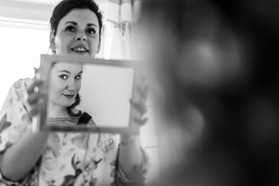 Préparatifs de la mariée qui sourit devant le miroir, coiffure bohème, Mariage Perros-Guirec
