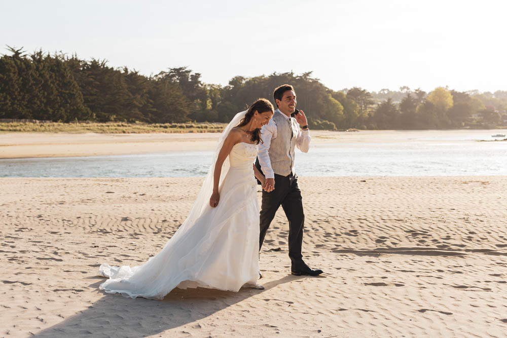 seance photo Trash the dress - couple marchant à la plage en tenue de mariés - Plestin les greves - coucher de soleil