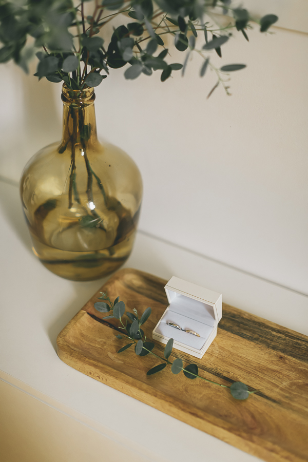 photos des alliances dans son ecrin chic, posé sur la table et décoré avec un bouquet d'eucalyptus