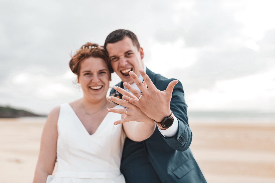 Les mariés très heureux d’être mariés montrent leurs alliances avec energie