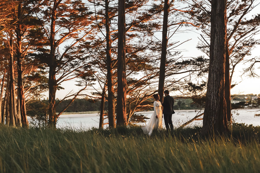 Les mariés dans les cyprès au coucher de soleil se partagent leurs voeux devant la baie de Locquirec. Romantisme