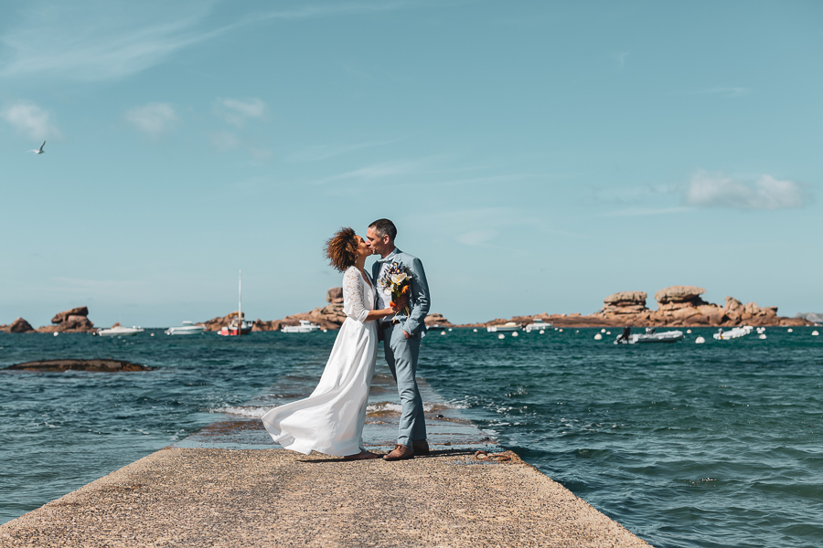 Couple qui s'embrassent sur la cale au Coz Pors de Trégastel et la mer les entourent