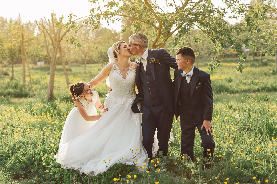photos de famille des mariés et de leurs enfants dans un vergers au soleil couchant