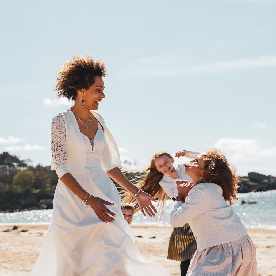 la mariée et sa fille s'amusent à la plage