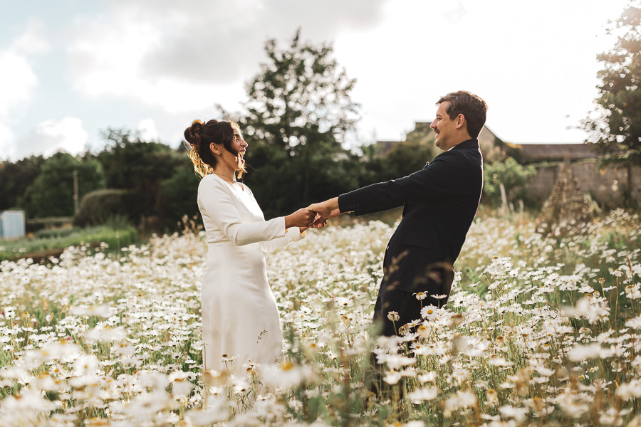 Les mariés dansent et s'amusent dans un champ de marguerites à Locquirec