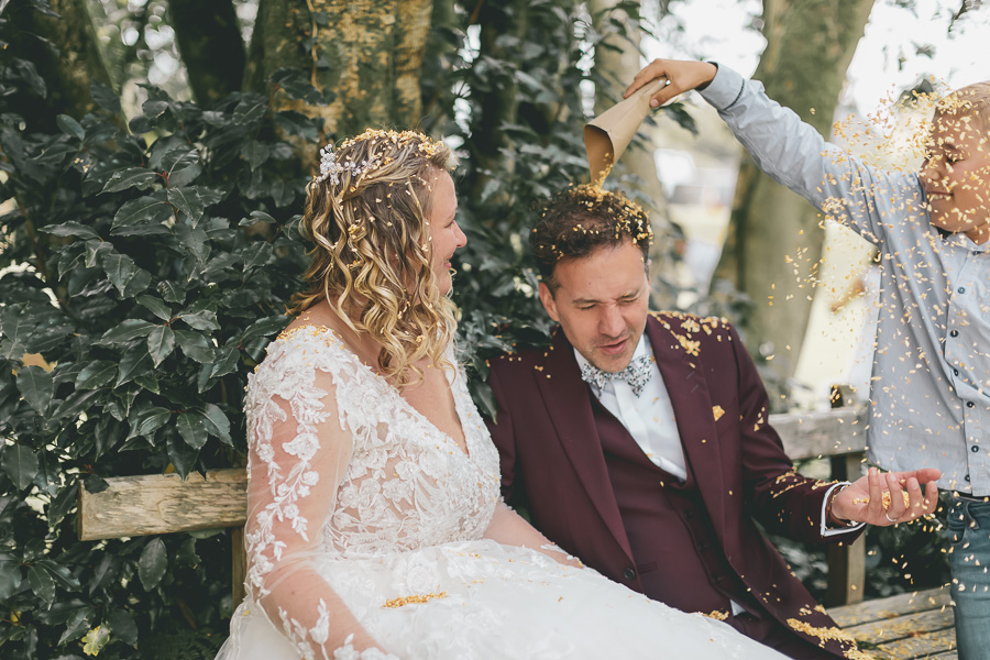 Les mariés se font arrosés avec des pétales de fleur par les enfants. Surprise et fun