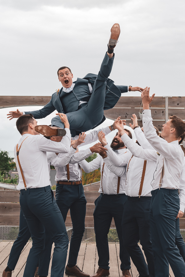 les garçons d'honneur font sauter le marié dans les airs, photo de groupe fun
