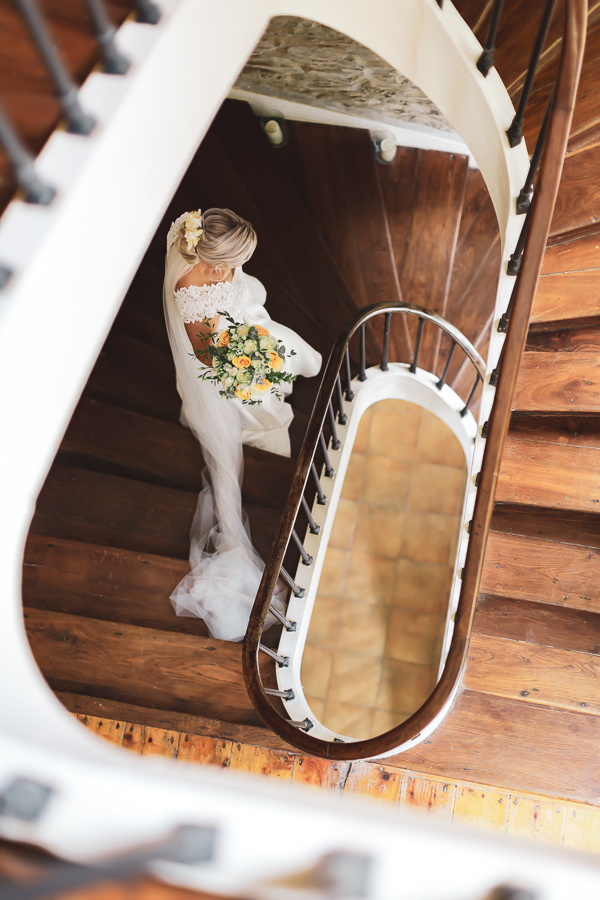la mariée descend les escaliers avec son bouquet, vue d'en haut, artistique
