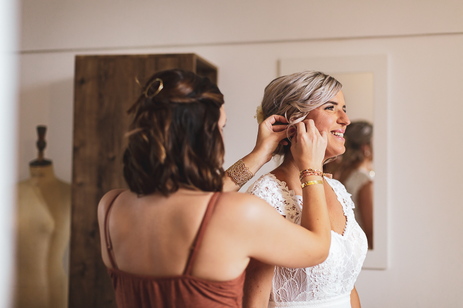 la témoin aide la mariée à mettre ses bijoux, complicité
