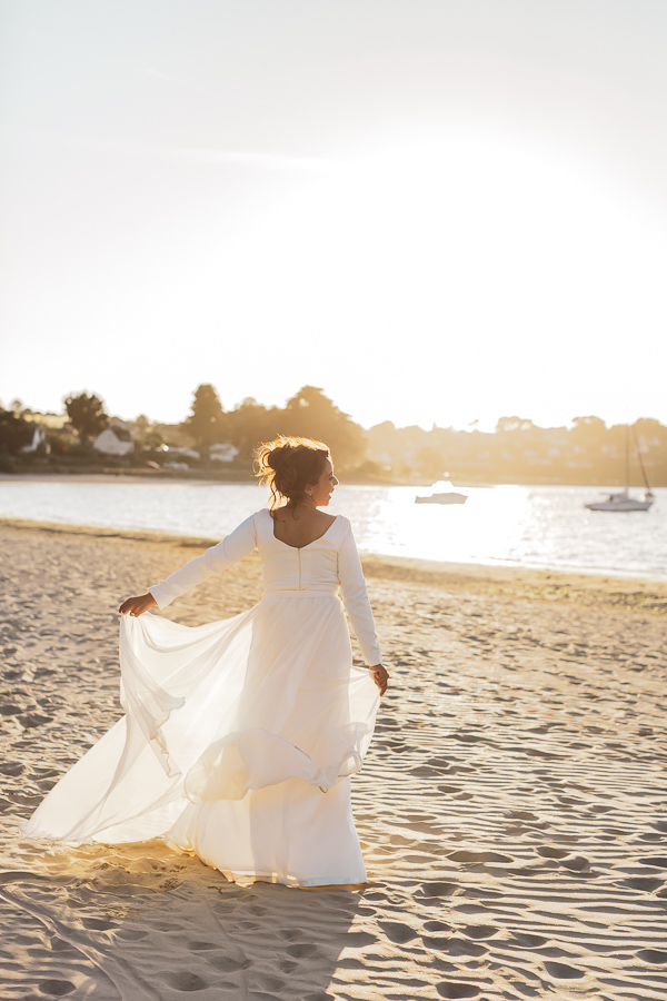 La mariée joue avec sa robe dans le soleil couchant à la plage de locquirec