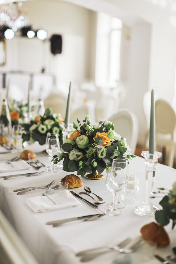 Décoration de table avec des bougies vert sauge et bouquet blanc et orange pale au chateau de Kerezellec