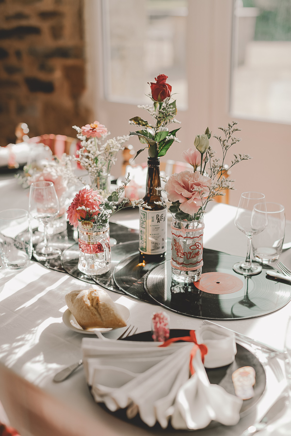 Décoration de table sur le thème de la musique avec des vyniles et des fleurs roses pales et rouge