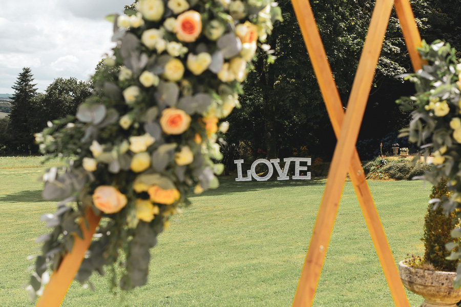 Décoration exterieur avec un LOVE lumineux et une arche en bois décoré de fleur