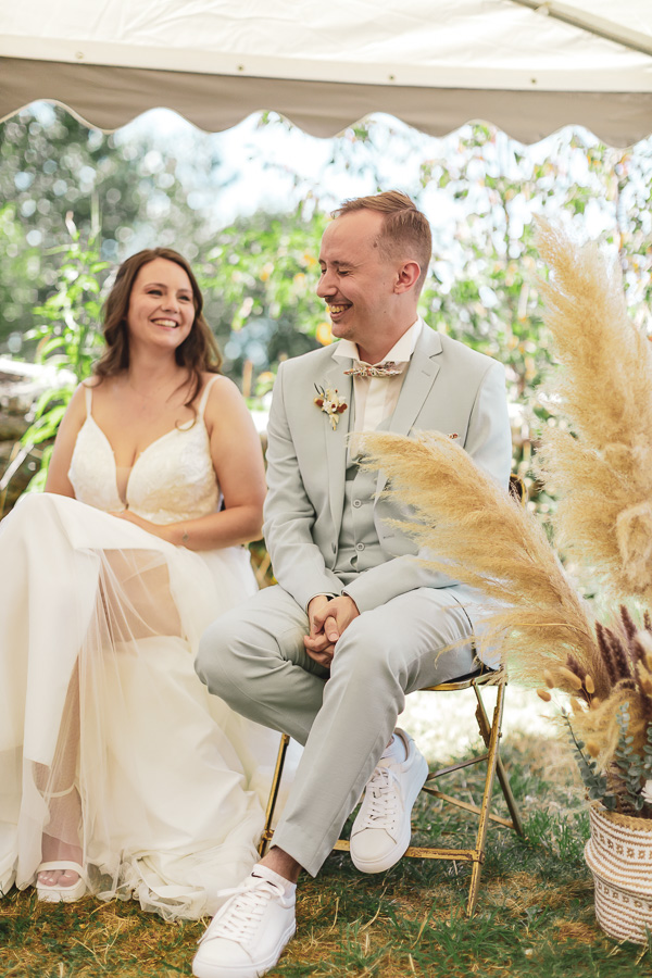 éclat de rire du marié lors de la cérémonie laique, habillé avec un costume couleurs vert sauge et basket