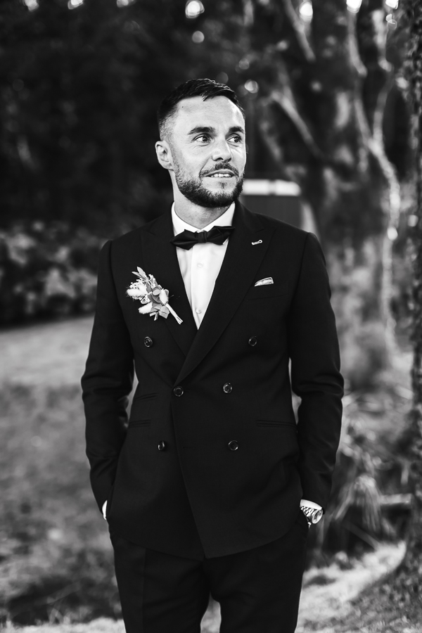 marié en costume noir élégant et chic qui regarde en direction de la mariée