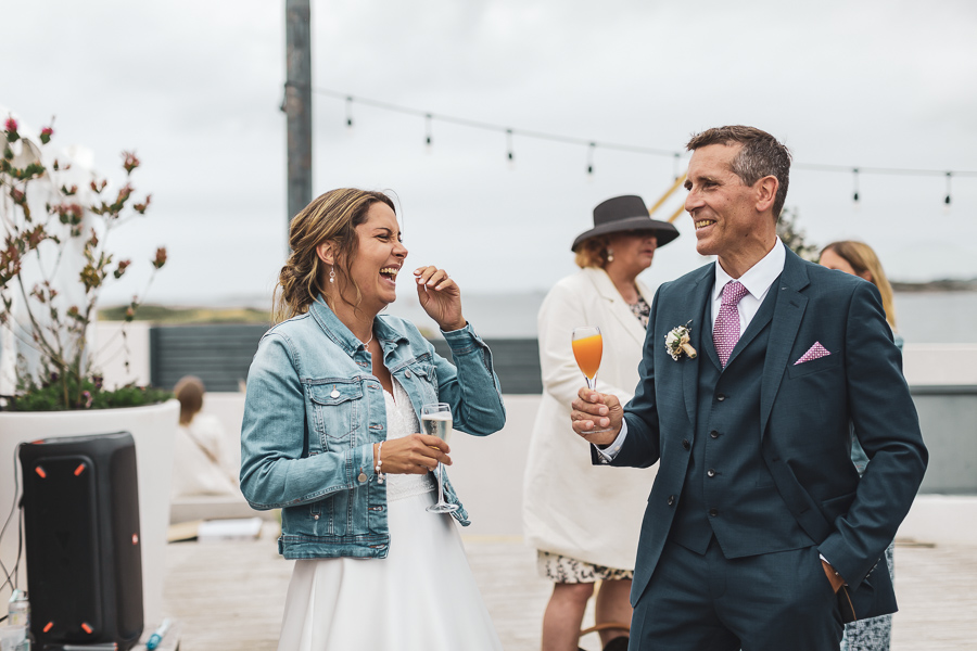 les mariés complices rigolent ensemble pendant le cocktail