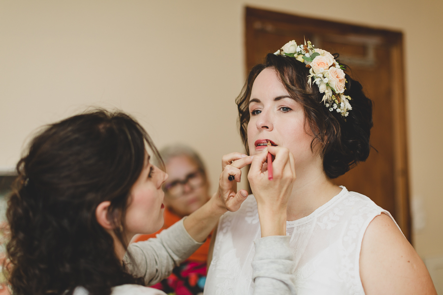 la mariée se fait maquiller, couronne de fleur dans les cheveux style bohème