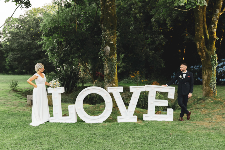 Les mariés se regardent avec le mot LOVE entre eux dans les jardins de Kerezellec