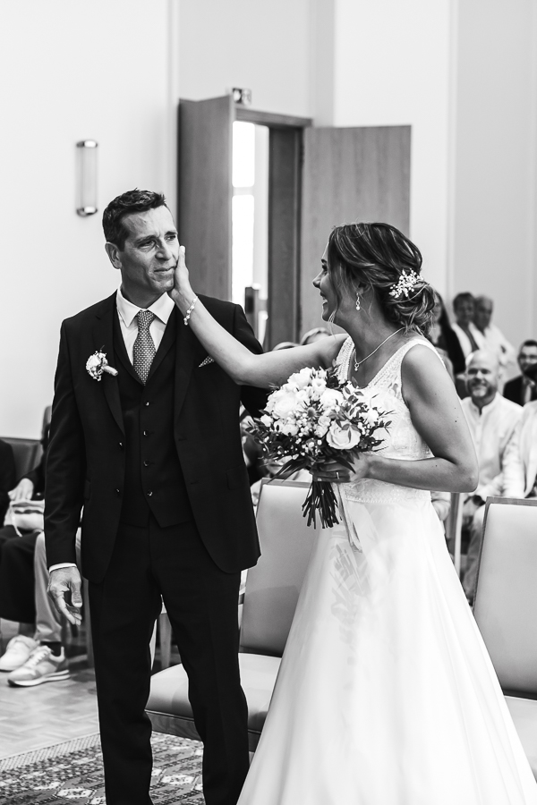 émotion et larmes de joie du marié a la mairie. La mariée pose la main sur la joue du marié