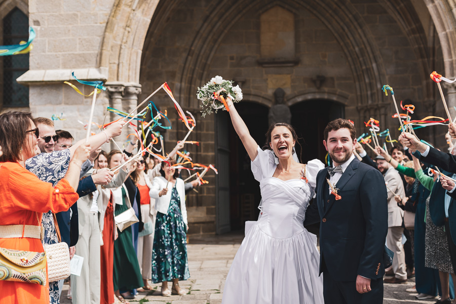 haie d'honneur pour les mariés heureux a la sortie de l'église avec des rubans