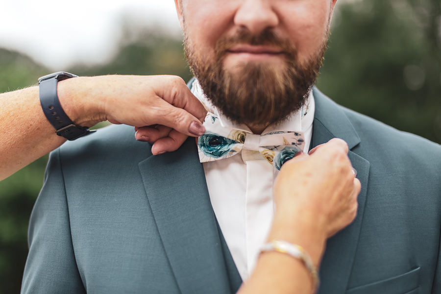 noeud papillon chic au cou du marié aidé par la maman