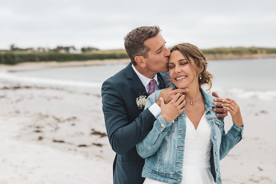 le marié fait un bisou à la mariée et la mariée souri. Sensualité et amour sur la plage