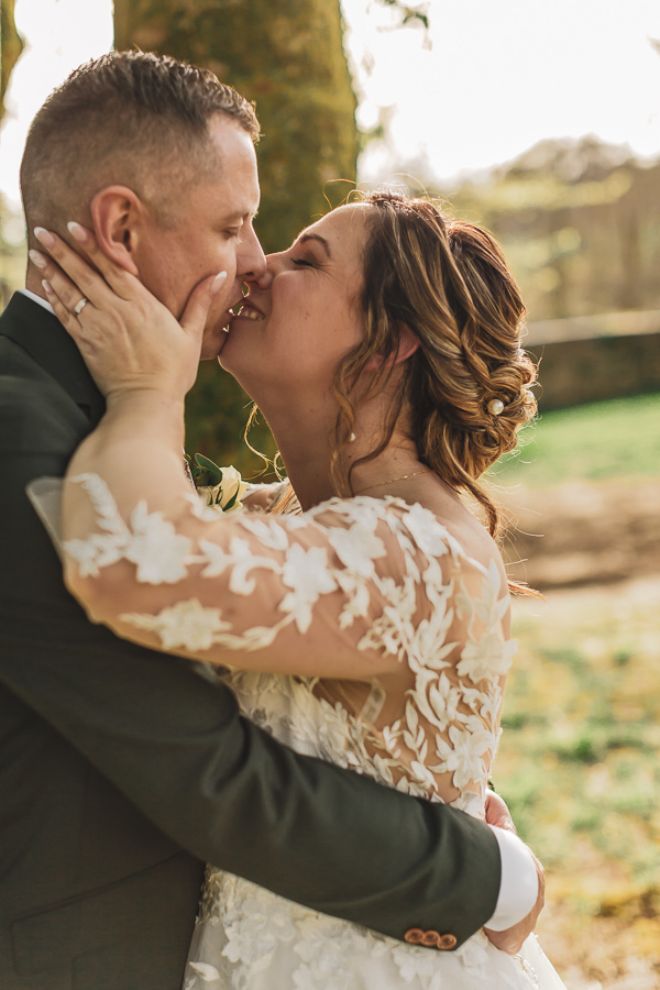 Couple de mariés enlacés et qui s'embrassent. Complicité et amour dans les jardins du manoir de Kerleguer