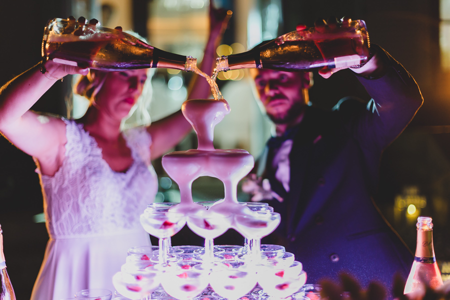 Les mariés servent les coupes de la fontaine de champagne devant le château de Kerezellec