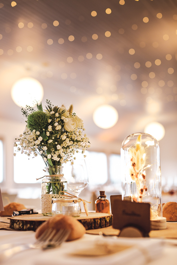Décoration de la salle de réception avec des bouquet de fleurs blanches et des guirlandes lumineuses. Les Terrasses de l'Aber