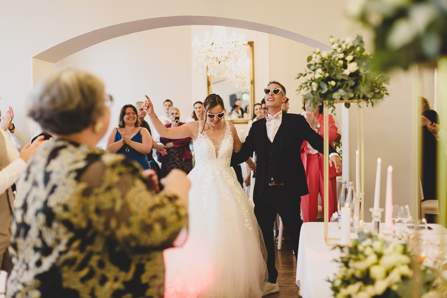 Entrée des mariés dans la salle du château de kerezellec. Les mariés ont des lunettes de soleil fun en forme de coeur