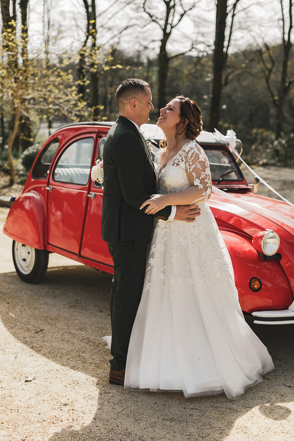 couple de mariés amoureux devant une voiture 2 chevaux au manoir de Kerleguer