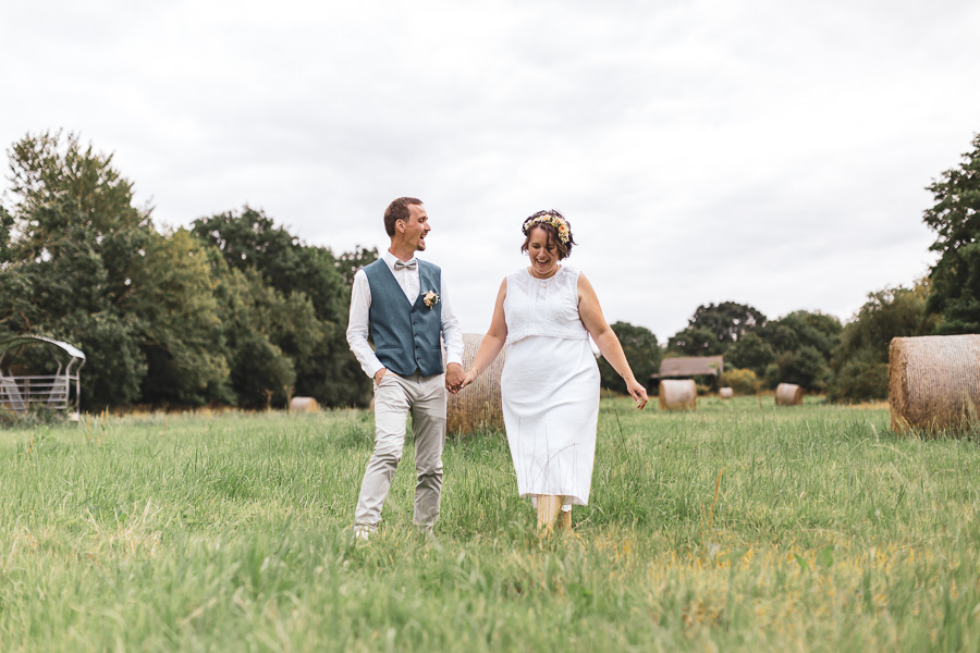 Les mariés marchent et s'amusent dans un champ avec des bottes de pailles à Ploumilliau