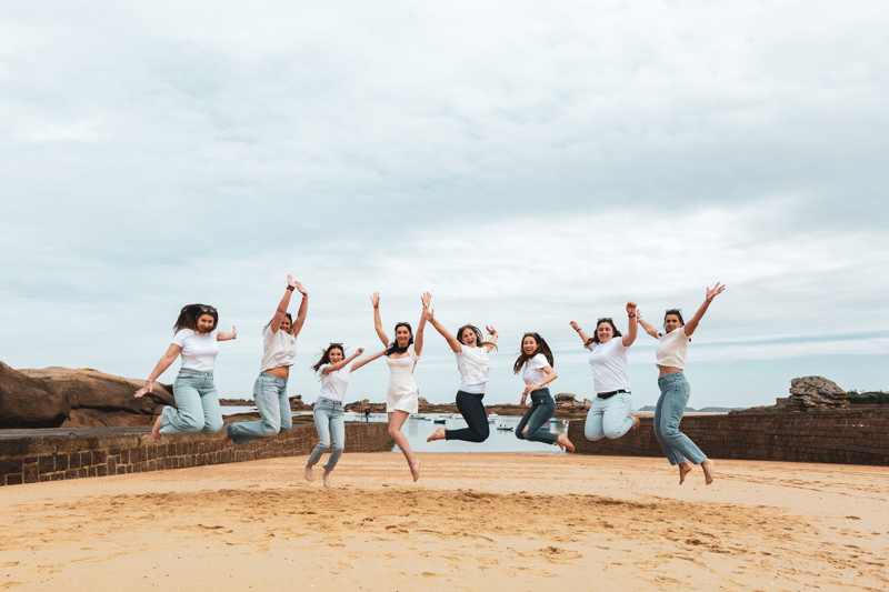 les filles et la future mariée sautent toute ensemble sur la plage pour une photo de groupe fun