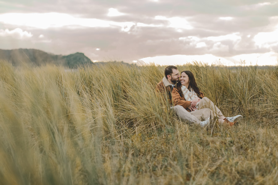 couple assis dans les dunes, tendresse et complicité pendant la seance photo