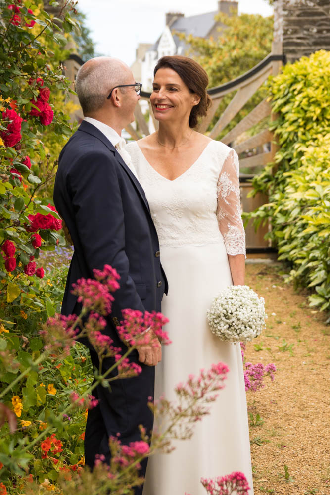 couple mariage photographe Couple marié prend la pose devant des fleurs