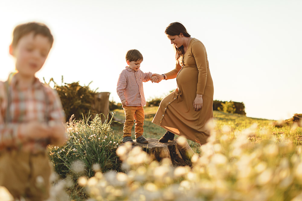 femme enceinte avec ses enfants au milieu des fleurs au coucher de soleil