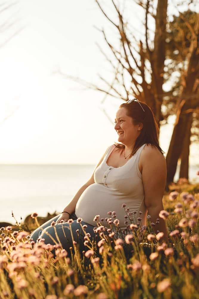 femme enceinte assise dans les fleurs joyeuse dans le soleil du soir