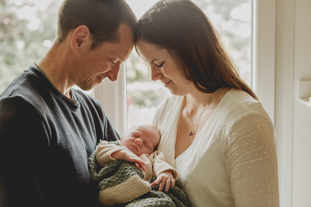 parents dans la lumiere qui regardent leur bébé avec le sourire