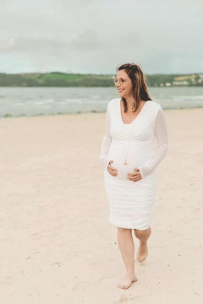 femme enceinte marche sur la plage sourire et détente