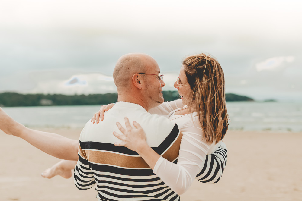 femme enceinte porté par son conjoint a la plage, moment de complicité en couple